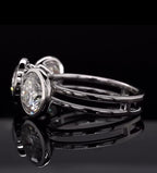 High-angle side view showing the split shank band and bezel cup construction of a white gold ring