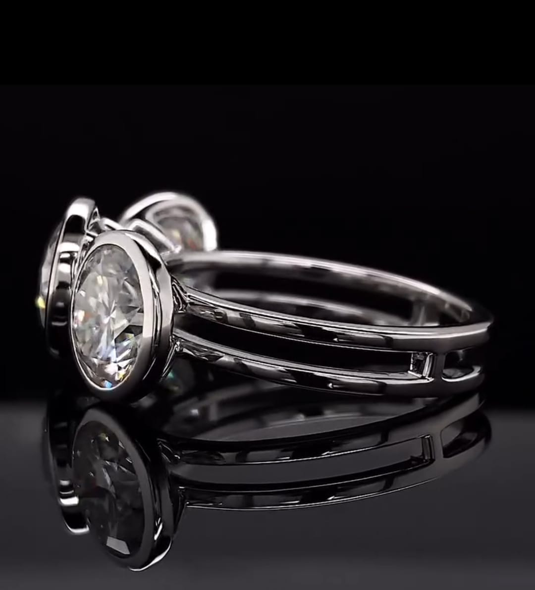High-angle side view showing the split shank band and bezel cup construction of a white gold ring
