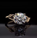 Top-down front view of 3 CT round cut lab grown diamond engagement ring on black reflective background.