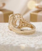 A yellow gold filigree ring with a clear rectangular gemstone, milgrain-edged bezel setting that accentuates its step-cut facets.
