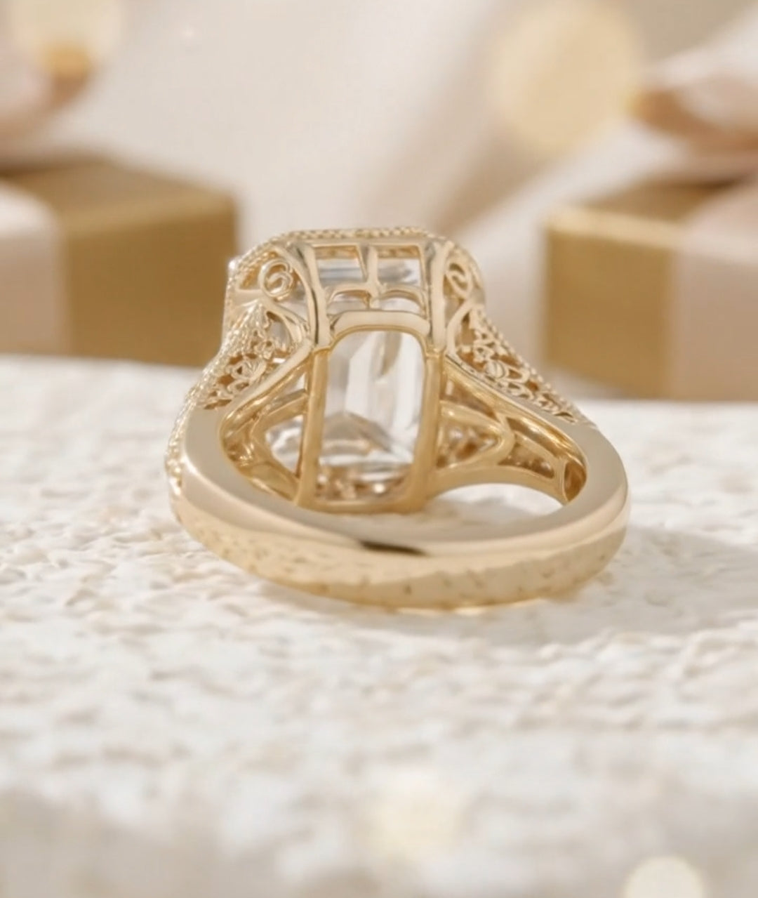 Side profile of a vintage gold engagement ring with a large emerald cut gemstone and accent diamonds on a filigree band