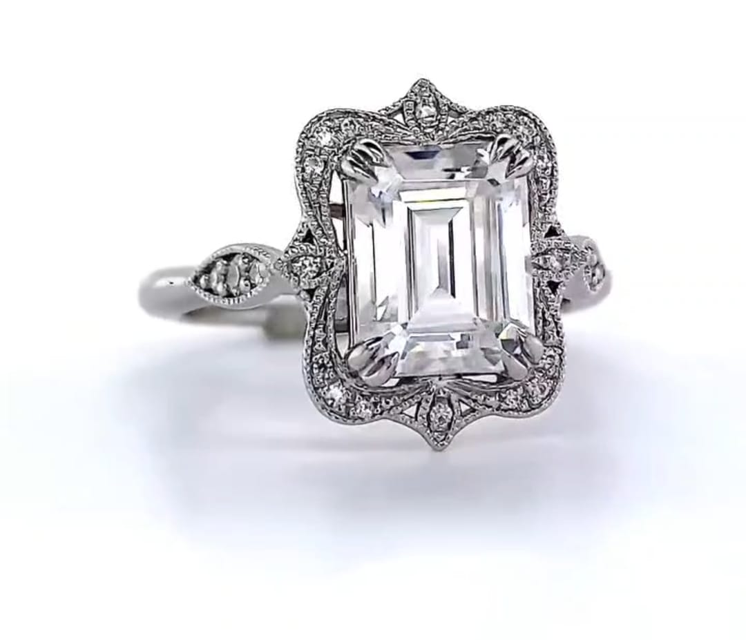 Front view of emerald cut lab diamond engagement ring with ornate scalloped frame and leaf accents.