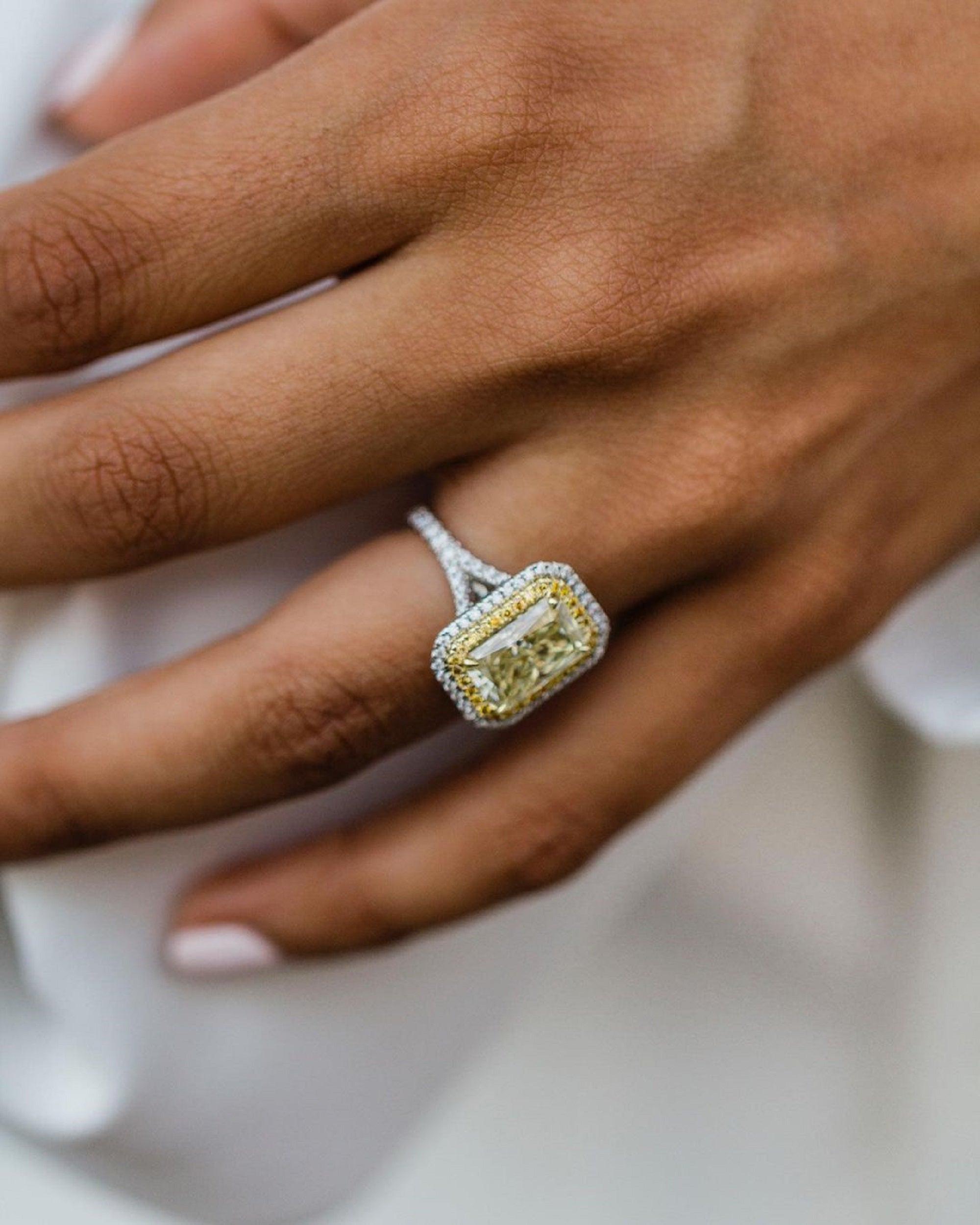 Detailed close-up view showcasing the two-tone setting, yellow radiant diamond, and diamond-encrusted band.