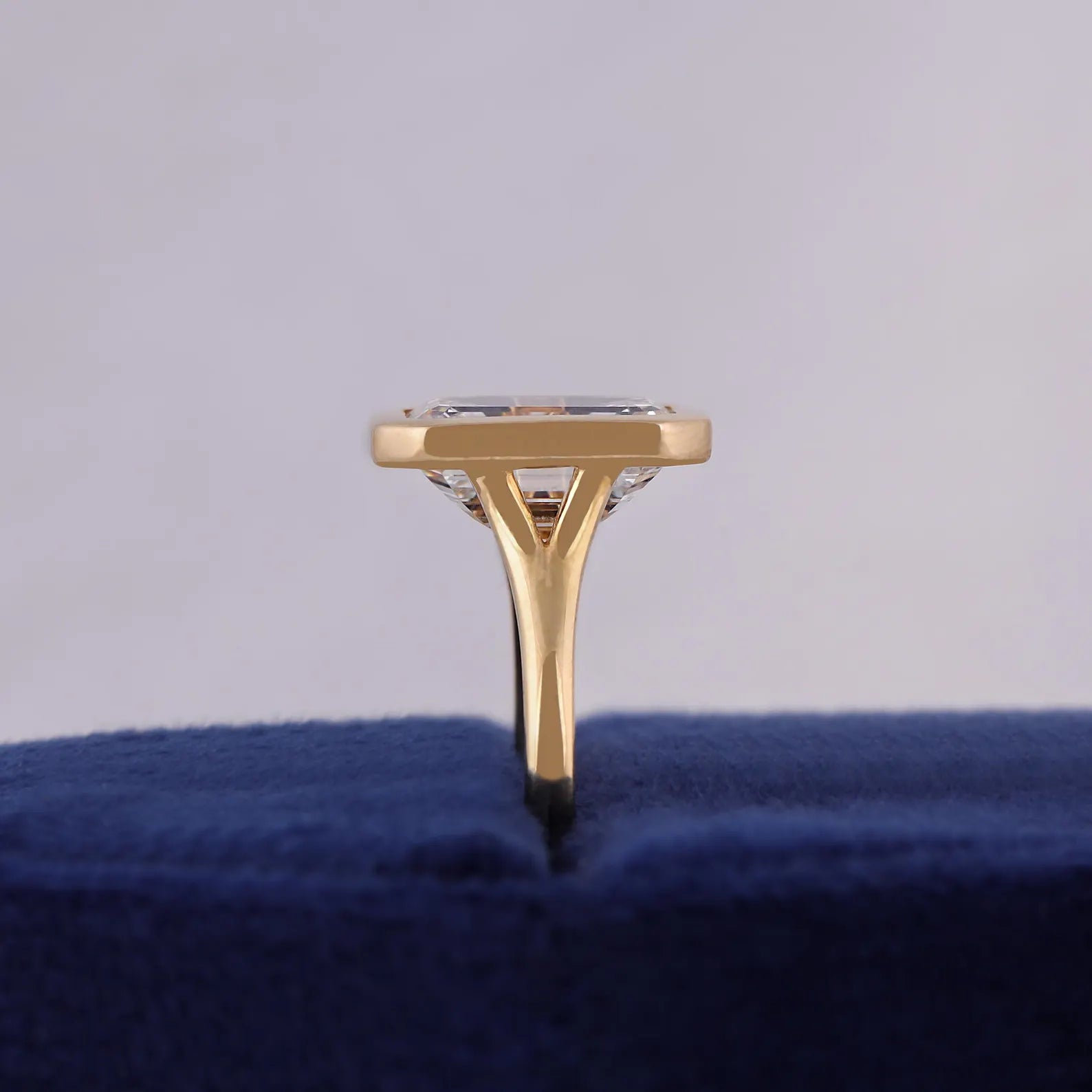 Direct side-profile view displaying the low-profile bezel setting and split cathedral shank on blue velvet.