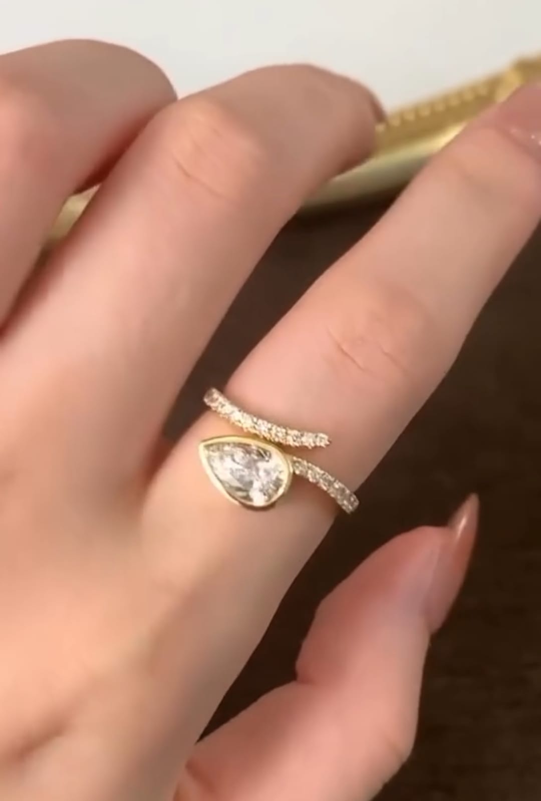 On-finger view displaying the 1.5 carat pear lab diamond in a full bezel setting on a yellow gold pavé wrap band.