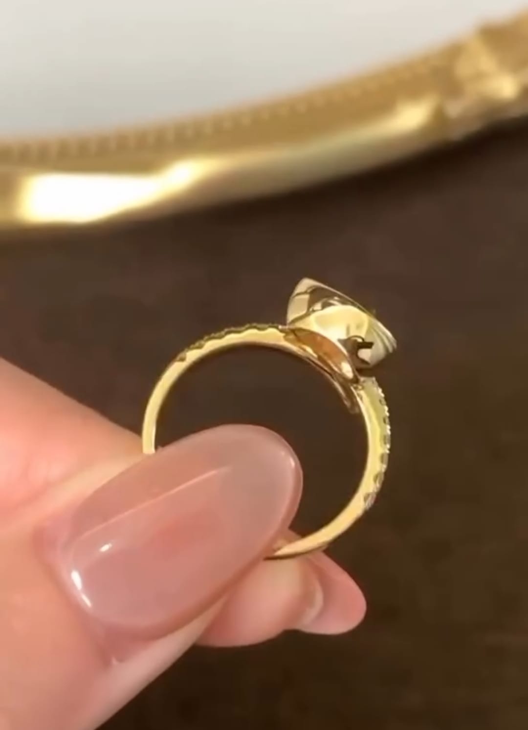 Side profile view showing the sleek low-profile gold bezel setting and smooth band structure of the pear diamond ring.