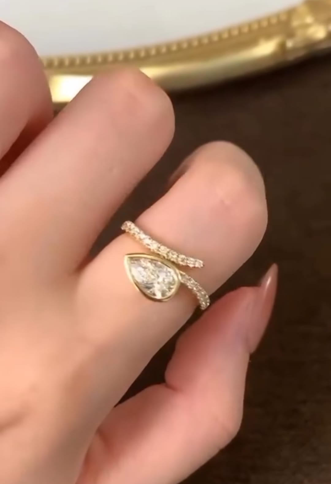 Hand view showing the unique asymmetrical bypass design and pavé diamond-accented band of the 1.5 CT pear lab diamond ring.