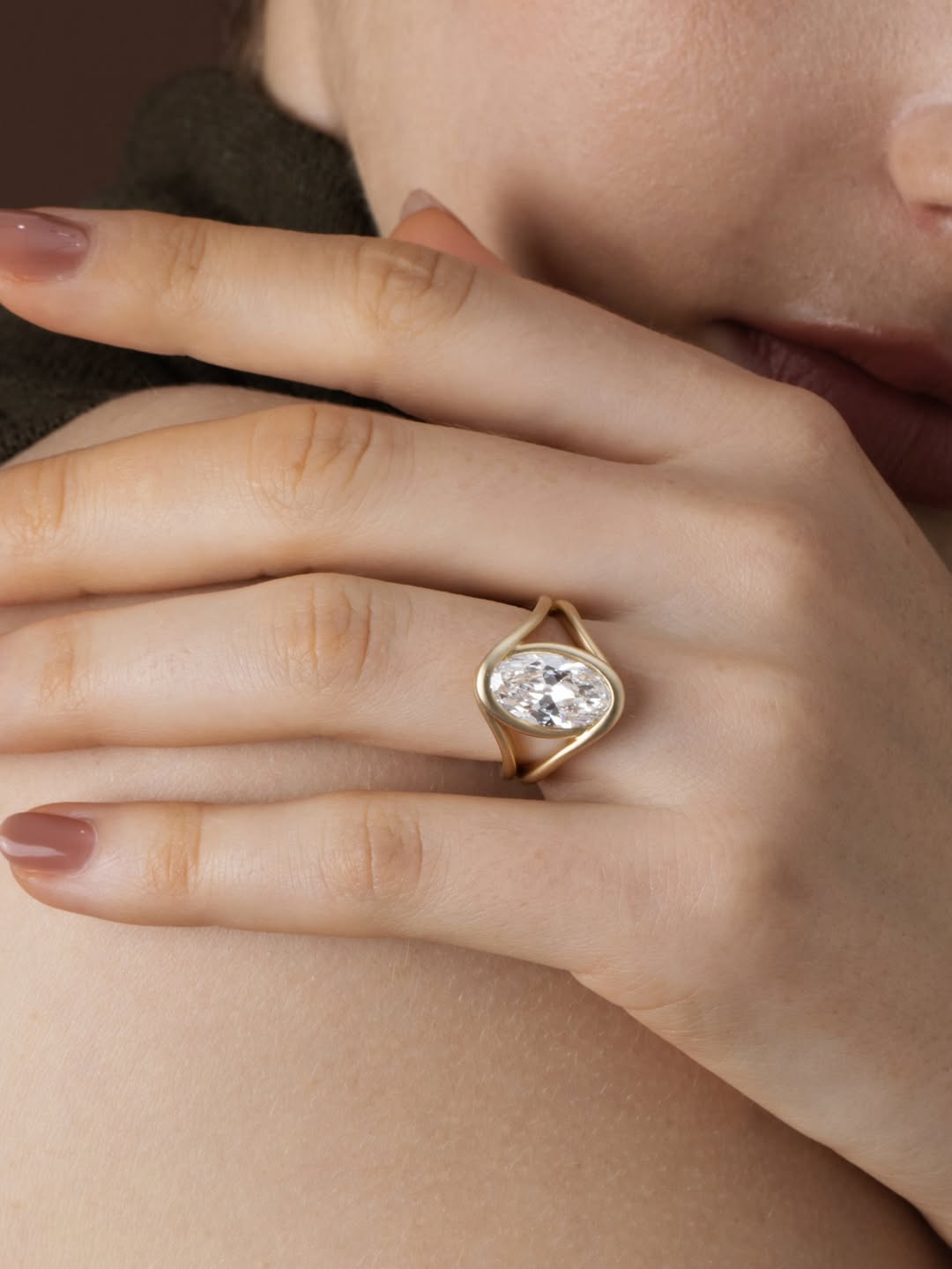 Lifestyle model shot featuring a 3 carat oval cut lab grown diamond ring with a matte yellow gold organic bezel setting