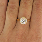 Top-down view on hand of a 2 carat round lab grown diamond ring with yellow gold milgrain halo setting