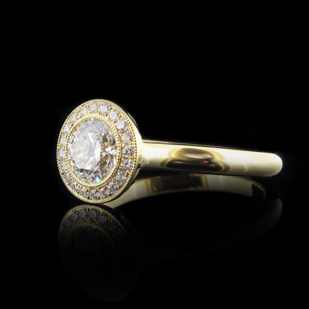 Side perspective of a round lab diamond engagement ring with a yellow gold plain band and milgrain halo