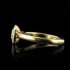 Direct side view of a 2 carat round lab grown diamond halo ring resting on a reflective surface