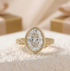 Three-quarter view of a gold oval bezel engagement ring highlighting the open filigree undergallery and engraved band