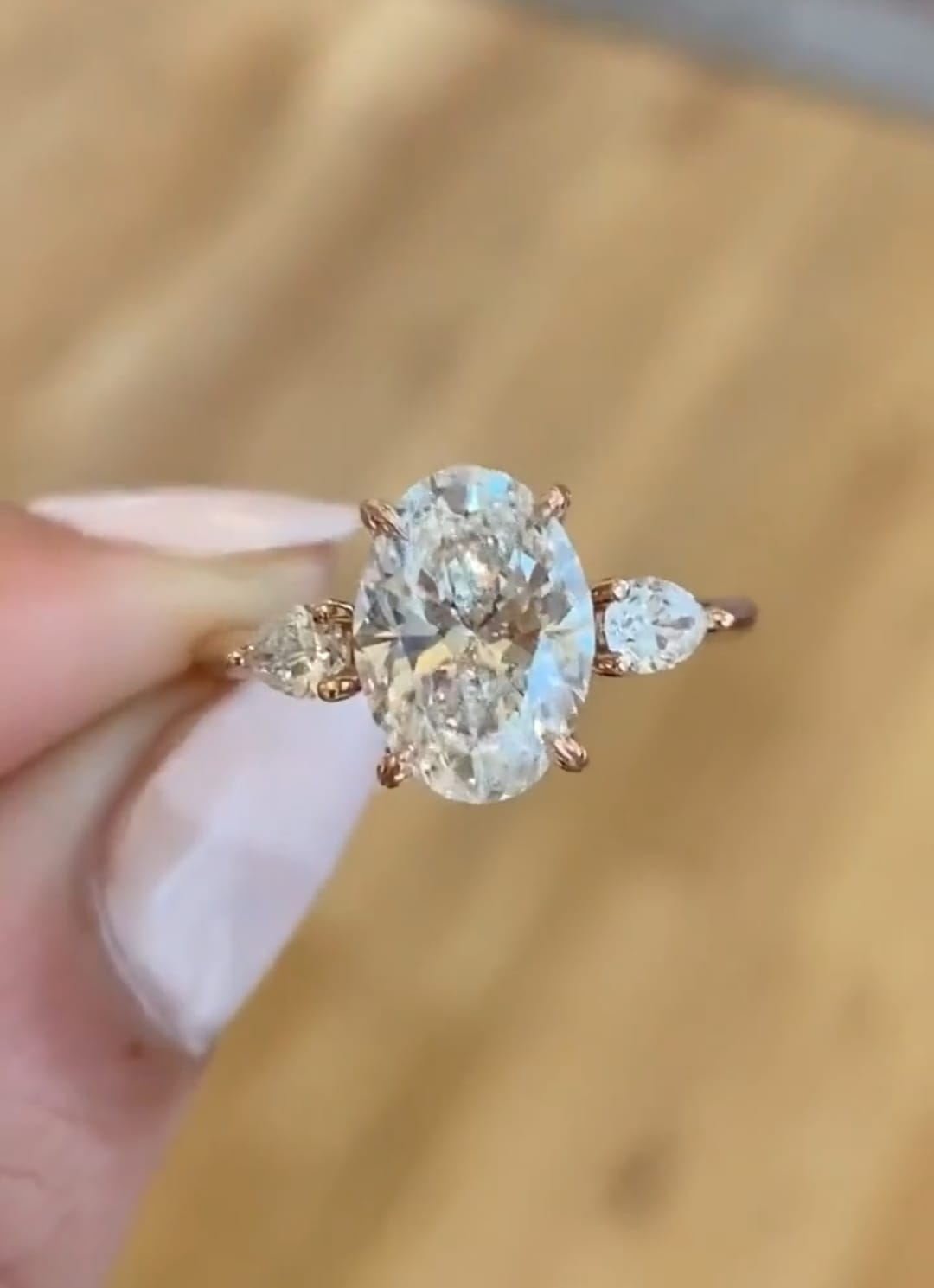 Macro detail view of 3 carat oval lab grown diamond and pear side stones in rose gold setting