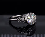 Three-quarter view showing 3 carat round lab diamond in bezel setting with scrollwork side accents