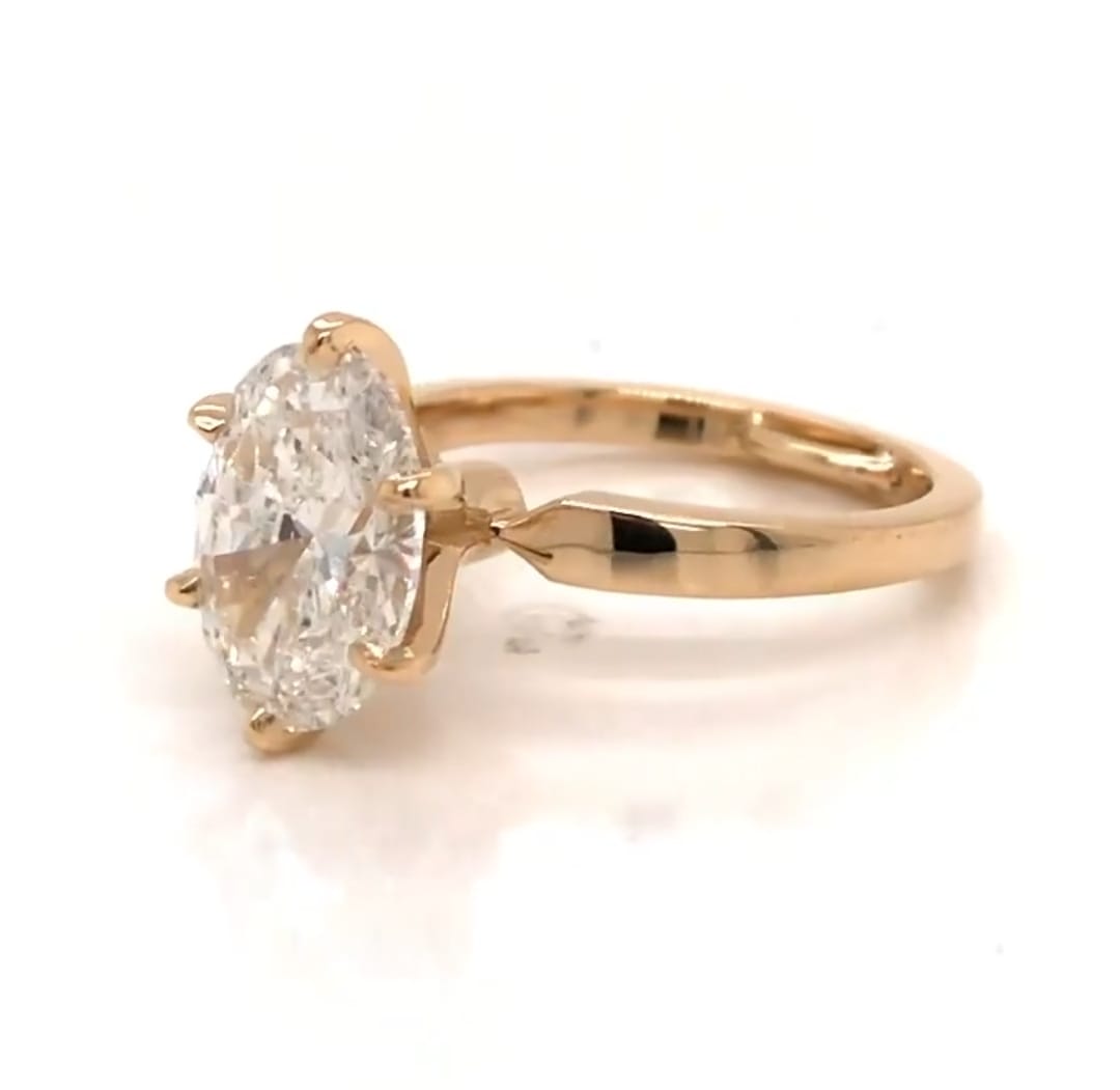 Elevated view showing 3 CT oval lab diamond held securely in 6 prongs on yellow gold band