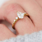 2 carat pear cut lab-grown diamond engagement ring worn on a finger in yellow gold.