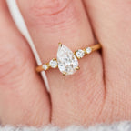 Top-down view of a 2ct pear-shaped lab-created diamond ring with accent diamonds on a finger.