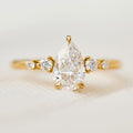 Front macro view of a 2 carat pear cut lab-grown diamond ring set in 14K yellow gold with tapered side gems.