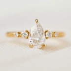 Front macro view of a 2 carat pear cut lab-grown diamond ring set in 14K yellow gold with tapered side gems.