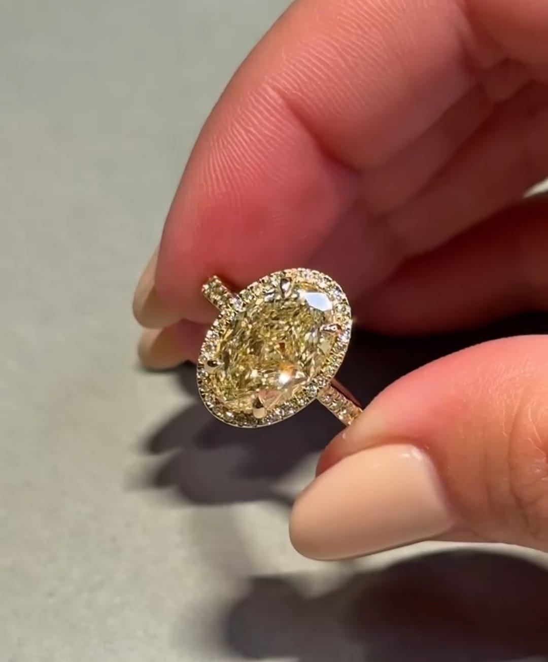 3 carat fancy yellow oval lab-grown diamond halo engagement ring worn on a finger.