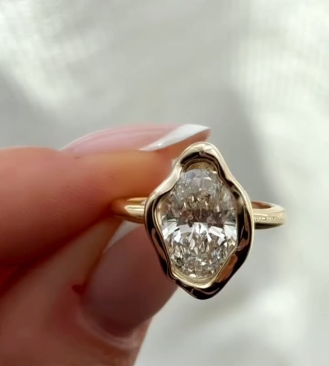 Perspective view highlighting the glossy, curved edges of an oval lab-grown diamond wavy bezel setting.