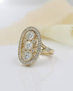 Angled side view of a yellow gold vintage-inspired diamond ring showing intricate filigree, milgrain edges, and accent diamonds set into the tapered band.