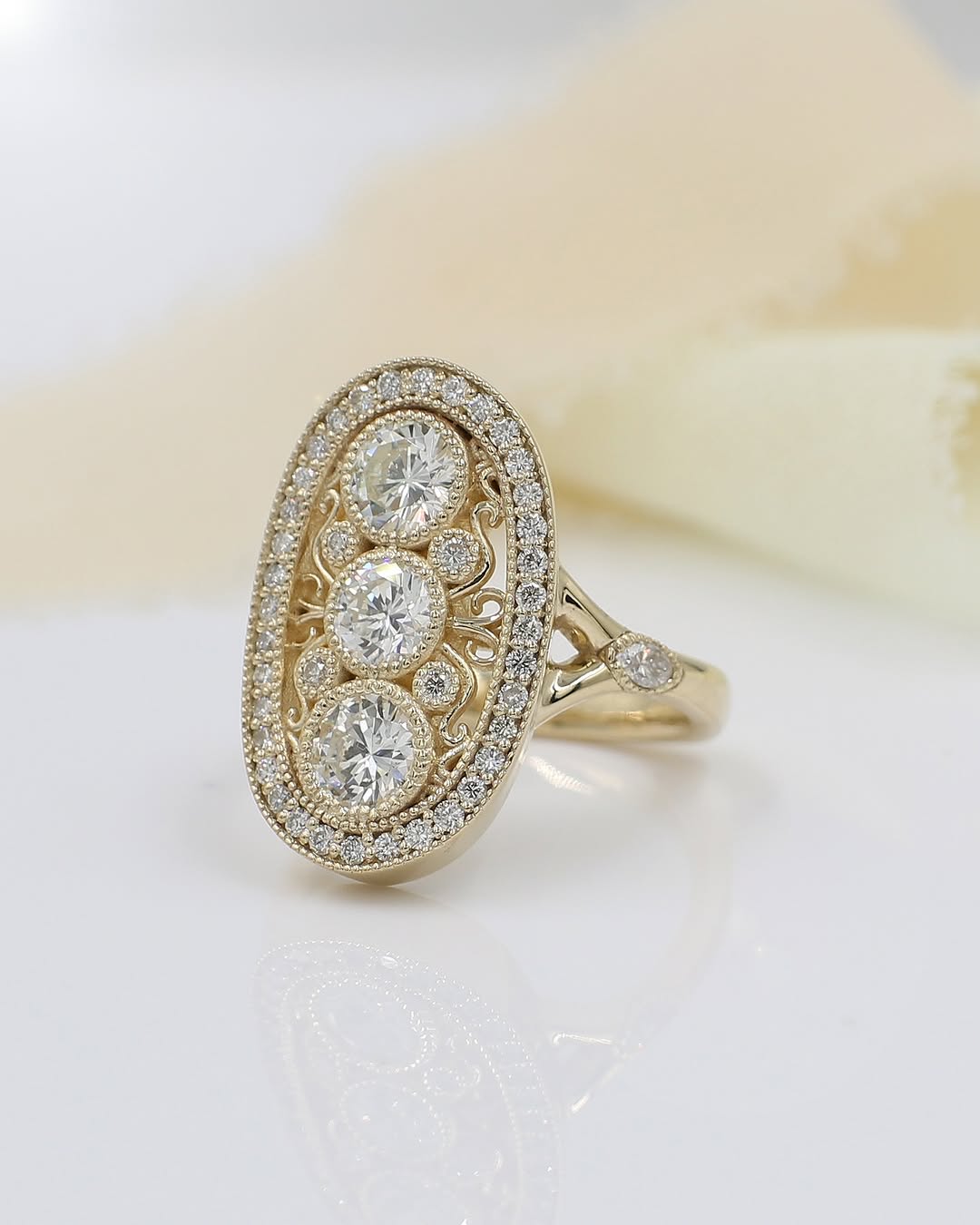 Angled side view of a yellow gold vintage-inspired diamond ring showing intricate filigree, milgrain edges, and accent diamonds set into the tapered band.