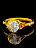 Top-down angled shot of a 2 carat round lab diamond ring in a yellow gold bezel setting