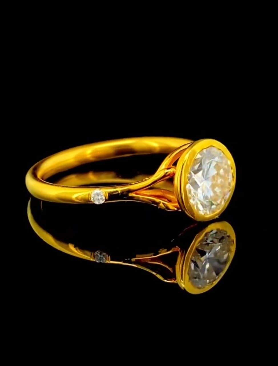 Close up perspective of a 2 carat round cut lab grown diamond bezel engagement ring in yellow gold