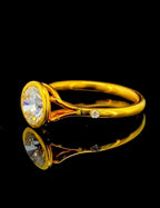 Side profile angle revealing flush-set accent diamond on the yellow gold band of a 2 CT round bezel ring