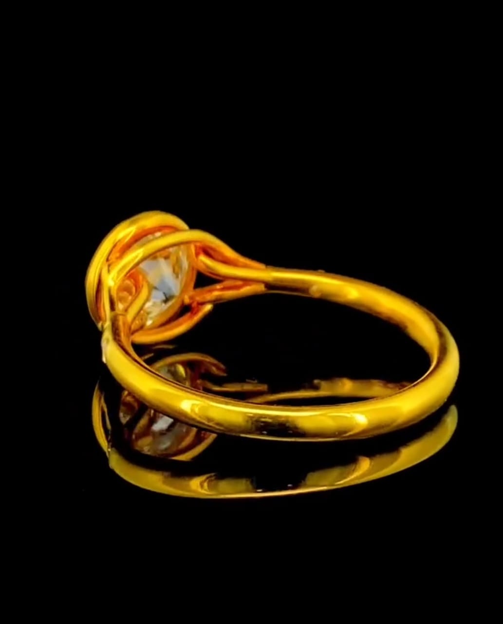 View of the open gallery and smooth yellow gold band structure on a 2 carat round lab diamond bezel ring