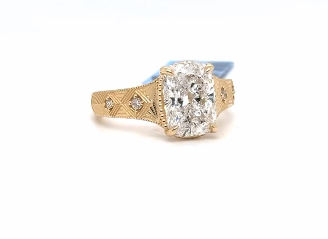 Angled view of a 3 CT elongated cushion lab diamond solitaire ring with milgrain engraved shank in yellow gold