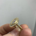 Side angle view showing the thin matte yellow gold band and bezel setting of the marquise diamond ring