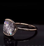 Top side view of a 3 CT cushion cut lab grown diamond engagement ring resting on a black background.
