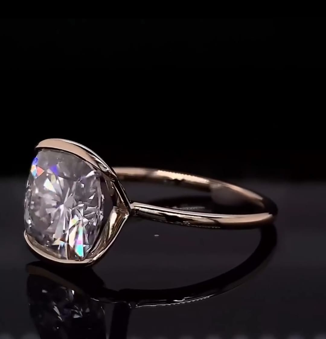 Top side view of a 3 CT cushion cut lab grown diamond engagement ring resting on a black background.