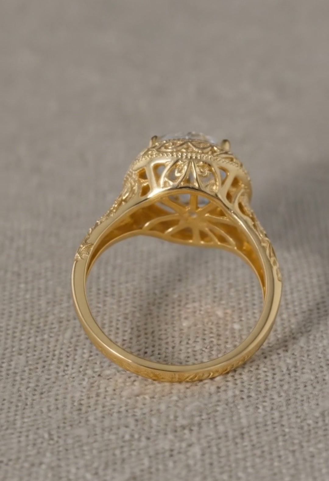 Under-gallery view of a yellow gold ring revealing the structural openwork basket design and deeply engraved patterns along the shank.