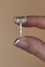 Side profile view of a yellow gold 3ct radiant cut diamond ring showcasing a sparkling pavé band and hidden halo detailing.
