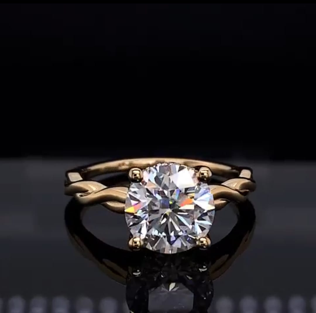 Front view of a 2 carat round cut lab grown diamond engagement ring featuring a twisted yellow gold band.