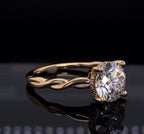 Angled side view of a yellow gold engagement ring showcasing the braided shank and hidden diamond halo under a 2 ct round center stone.
