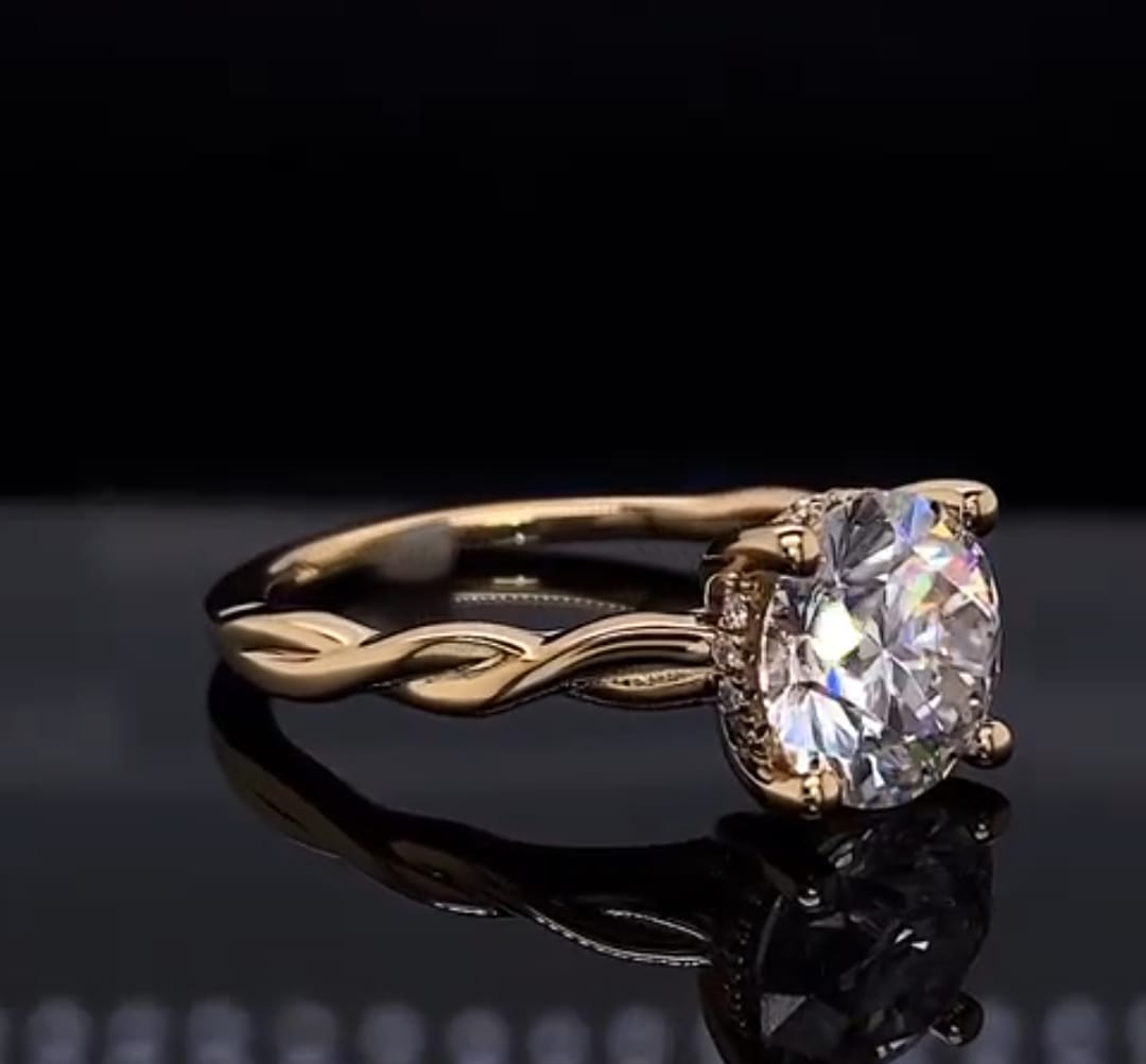Angled side view of a yellow gold engagement ring showcasing the braided shank and hidden diamond halo under a 2 ct round center stone.