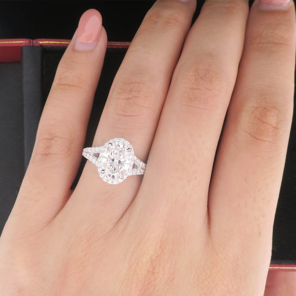 Top-down view of a 2 CT oval cut lab grown diamond halo ring worn on a woman's finger.