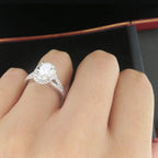 Close-up angled view of a 2 carat oval diamond halo engagement ring being worn on a hand.