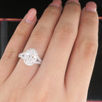 Hand modeling a stunning 2 CT oval lab grown diamond halo engagement ring over a red ring box.