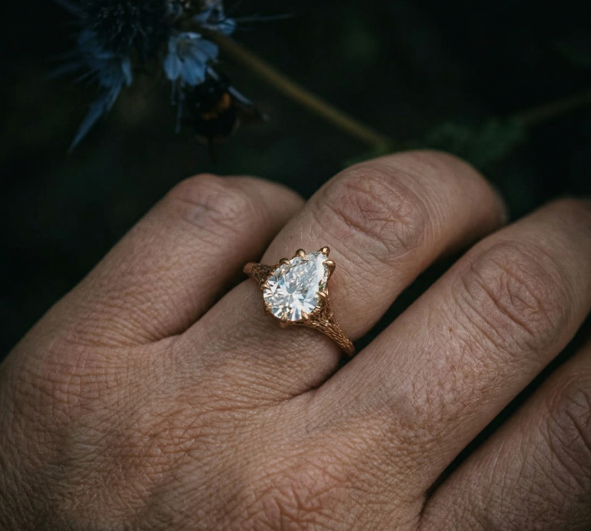 A beautiful 2 carat pear cut lab grown diamond engagement ring worn on a hand, highlighting the nature-inspired gold branch design.