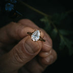 Top-down view of a 2 CT pear shaped diamond ring with a tree bark textured gold band against a dark natural background.