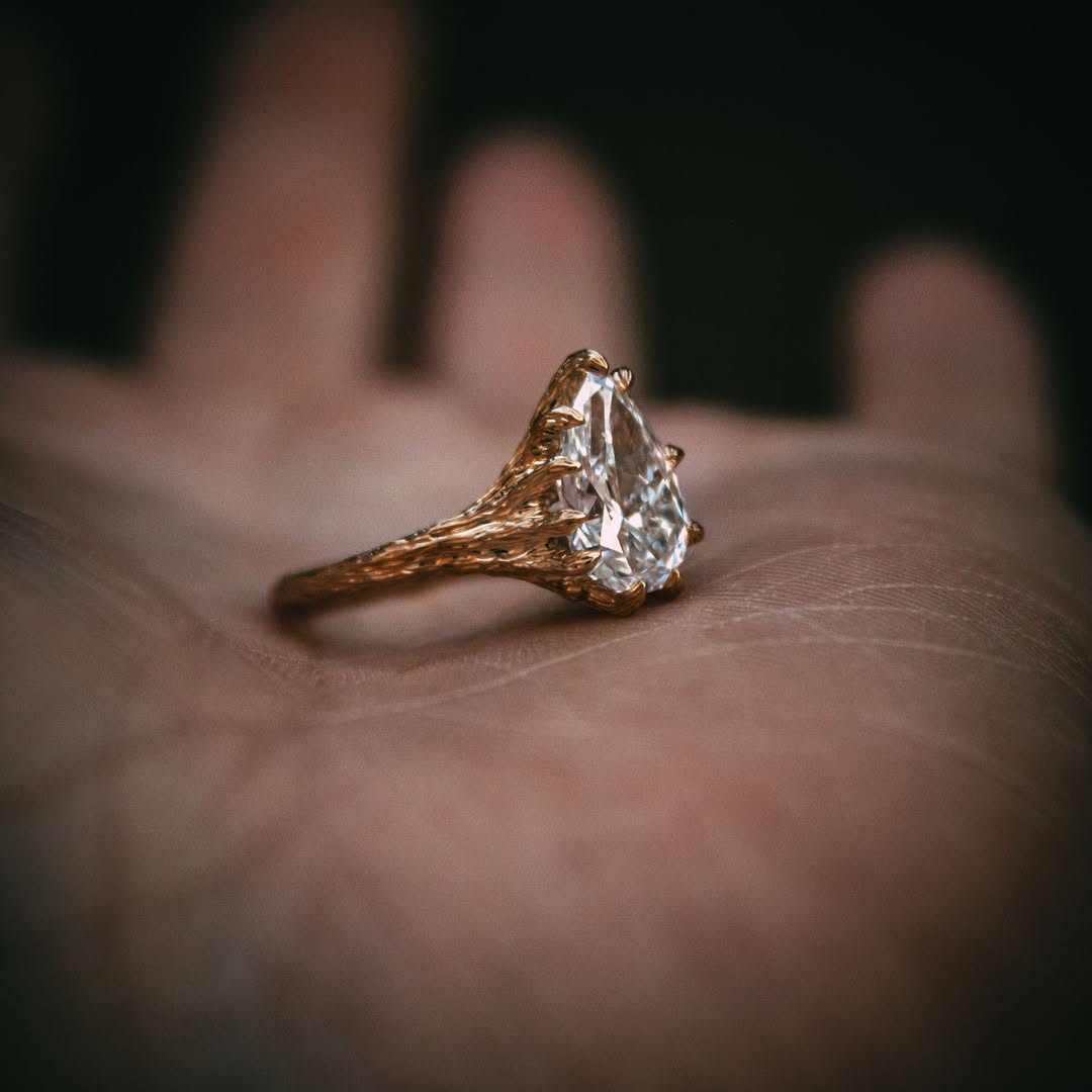 2 Carat pear cut lab-created diamond ring resting elegantly on a palm, showing the organic, detailed gold twig band.