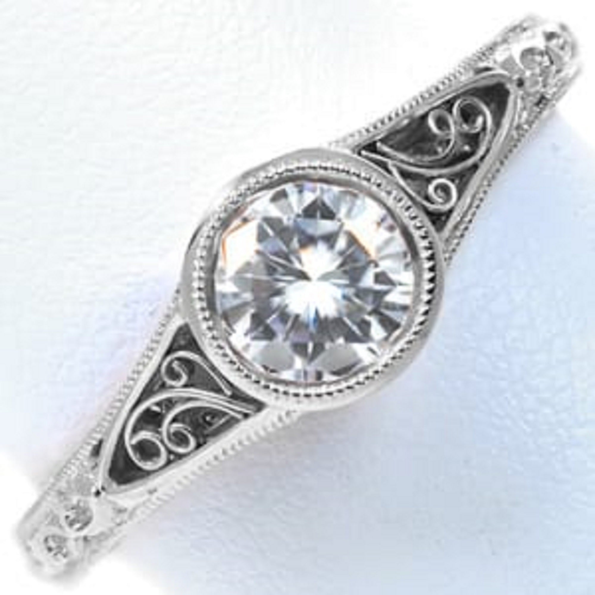 Vintage Art Deco round bezel engagement ring resting on a textured linen cloth next to dried eucalyptus leaves.