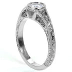 Close-up of a woman's hand wearing a beautiful vintage-inspired round bezel engagement ring with an intricate filigree band.