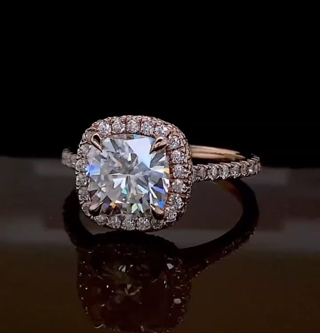 Close-up top-angled view of a 2 carat cushion cut lab grown diamond reflecting brilliant light in a rose gold halo setting.