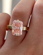 Close-up on-hand view of a 3 carat fancy pink radiant cut lab grown diamond engagement ring set in yellow gold.